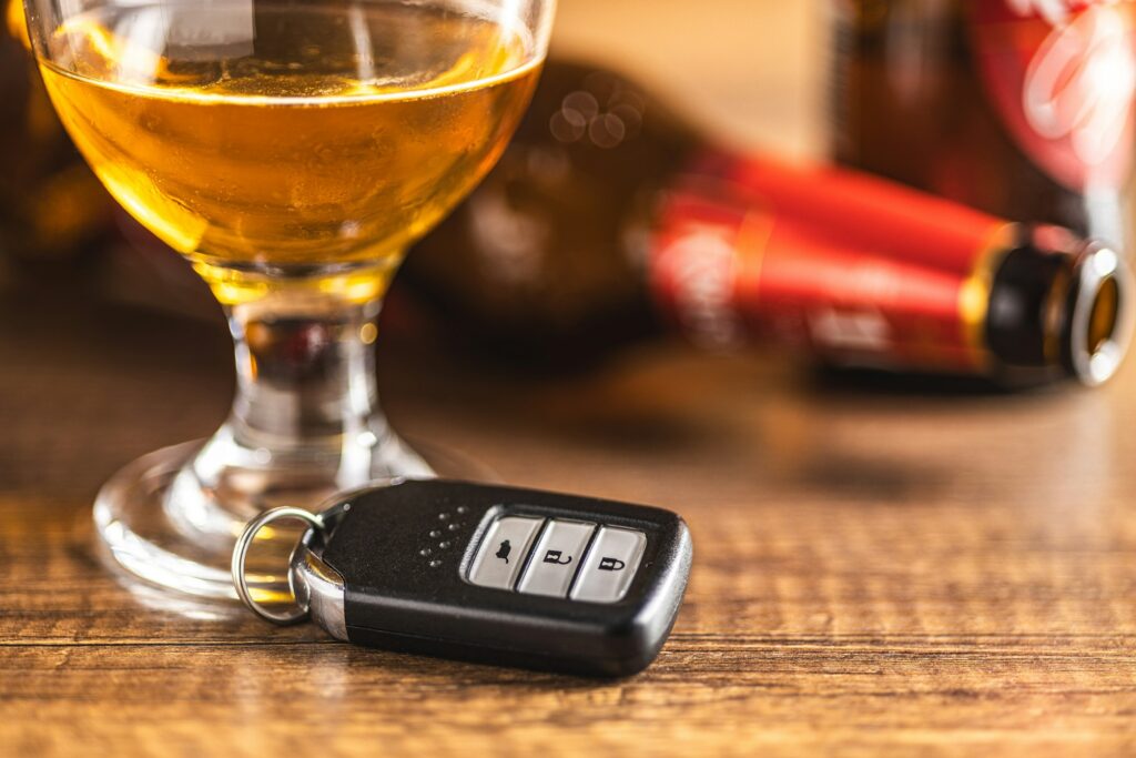 Car key with beer glass on wooden table. Booze driving concept. Drunk driver concept.